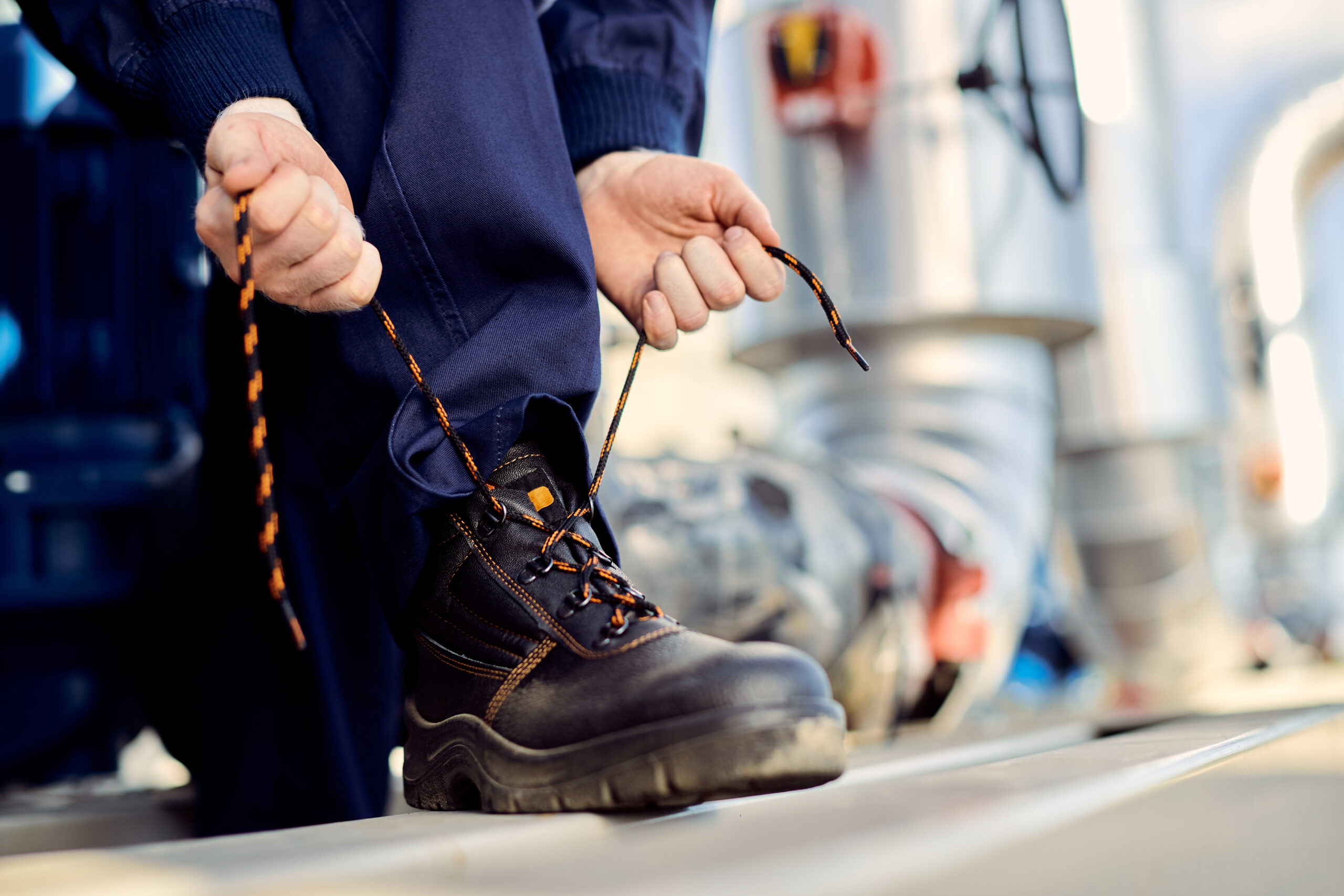 Sicherheitsschuhe S1: Optimaler Schutz von ATS Arbeitsschutz für Profis unrecognizable manual worker typing shoelace at construction sit