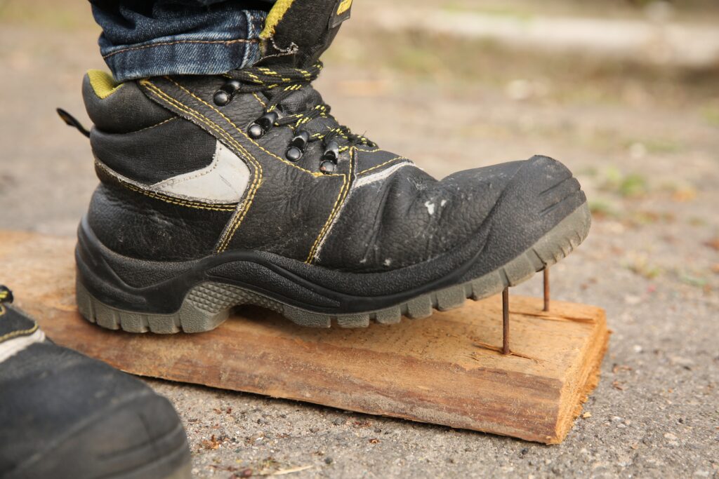 careless worker stepping on nails in wooden plank outdoors, closeup careless worker stepping on nails in wooden plank outdoors, closeup